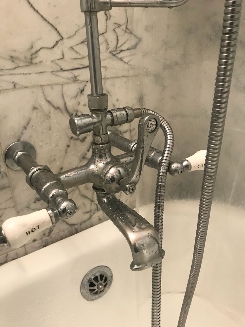 Restored antique tub filler against marble tile